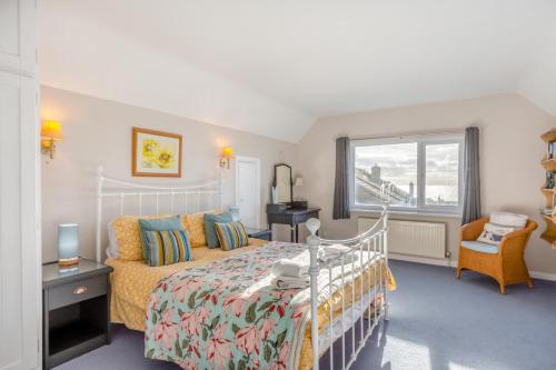a bedroom with a bed and a chair and a window at Sunshine Cottage - West Bexington in Swyre