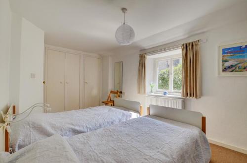 a bedroom with two beds and a window at Holly Cottage in Swanage