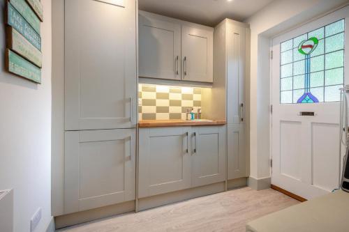 a kitchen with white cabinets and a window at Homelands in Studland