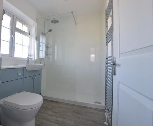 a white bathroom with a toilet and a sink at Sands in Swanage