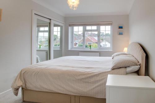 a white bedroom with a bed and two windows at Sands in Swanage