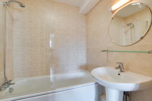 a bathroom with a sink and a tub and a mirror at Flat 6 Penlu in Swanage