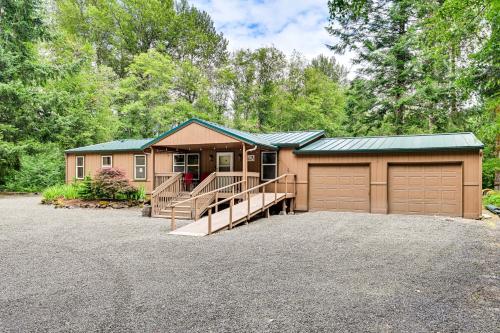 a house with a garage and a driveway at Gateway to Mt Rainier Riverfront Haven with Hot Tub in Packwood