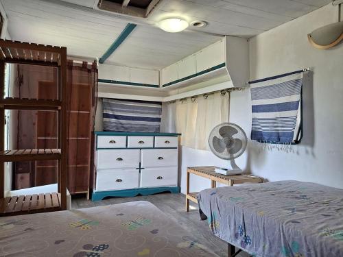 a bedroom with a bed and a dresser and a fan at Hébergements bohêmes pleine nature in Gignac