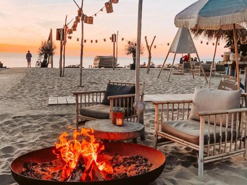 a fire pit on a beach with chairs and a table at Costa C en E in Noordwijk