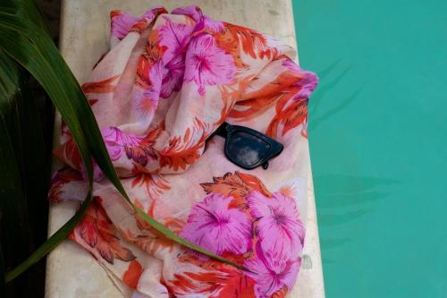 a scarf with pink flowers on it sitting next to a plant at Disfruta en La Casa de Lola / Enjoy at Lolas house in Progreso