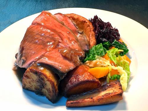 a plate of food with meat and vegetables on a table at The Old Pheasant in Glaston