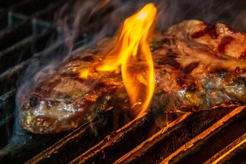 two pieces of meat cooking on a grill with flames at The Old Pheasant in Glaston