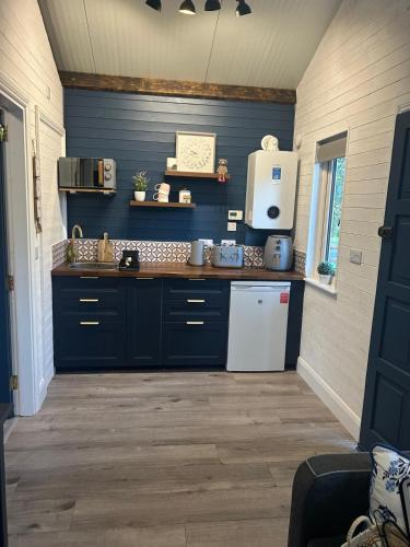 a kitchen with blue cabinets and a white refrigerator at Little Rock Cabin in Ballynagore