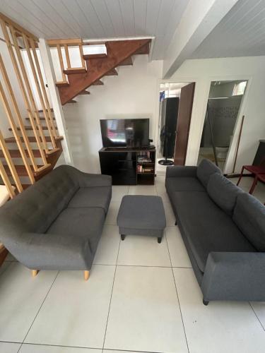 a living room with a couch and a tv at Maison Moehau Iti in Moorea