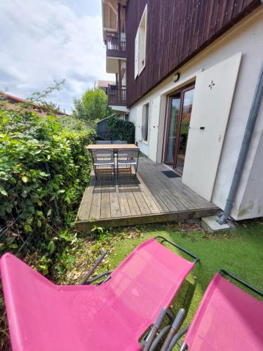 quelques chaises de jardin roses posées sur l'herbe dans l'établissement Bel appartement 2 pièces proche Arcachon, plage et port, à La Teste-de-Buch