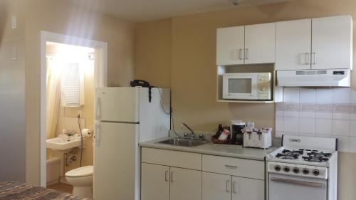 uma cozinha com um frigorífico branco e um lavatório em TC Motel em Medicine Hat