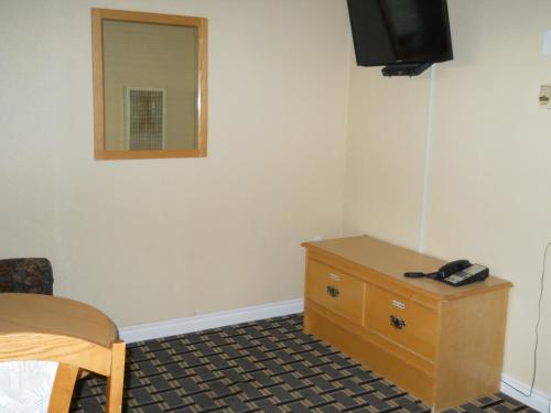 a room with a bed and a dresser and a mirror at TC Motel in Medicine Hat