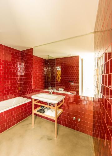 a red tiled bathroom with a sink and a tub at Melgaço Alvarinho Houses in Melgaço