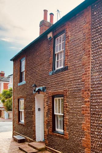 an old brick building with a white door and windows at Beautiful Old Cottage near the Seafront in Eastbourne
