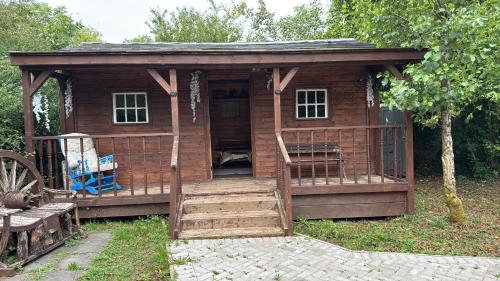 a wooden cabin with a porch and stairs in the grass at Willow Lodge in Llancarfan