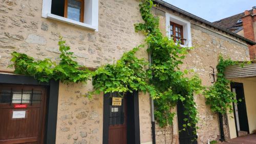 a building with green ivy on the side of it at Auberge de La Vielle Halle in Souppes-sur-Loing