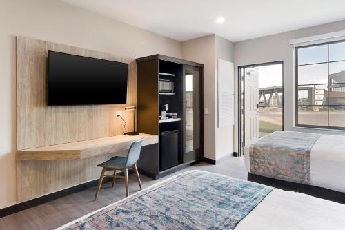 a bedroom with a bed and a television on a wall at ClubHouse Hotel & Suites Rapid City in Rapid City