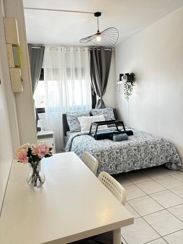 a bedroom with a bed and a table with a vase of flowers at Studio cosy avec vidéoprojecteur, à 100m du métro in Saint-Ouen