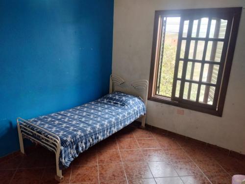 a small bed in a blue room with a window at Los jazmines in Resistencia