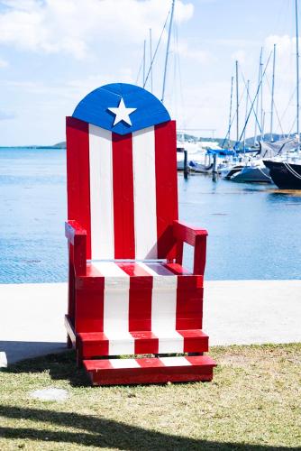 a red white and blue chair sitting next to the water at Isleta Marina- Paraíso Costero in Fajardo