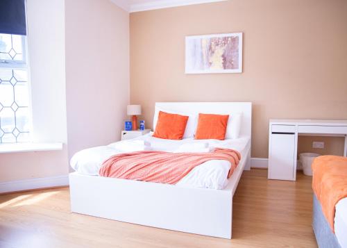 a white bed with orange pillows in a bedroom at CONTRACTOR READY - spacious and bright 5 bed house! in Luton