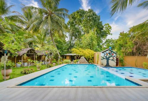 a swimming pool in a resort with palm trees at Mandavilla Airport Transit Hotel in Katunayake