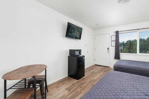 a bedroom with a bed and a table and a window at Sea Echo Motel in Lincoln City