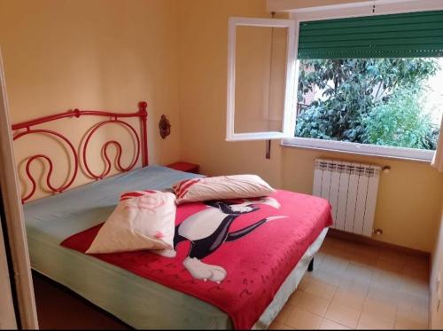 Un dormitorio con una cama con una manta roja y una ventana. en Casa della Costa - Porto Ercole Mare-, en Porto Ercole