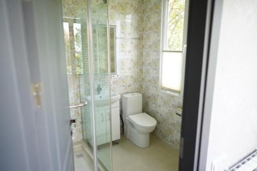 a bathroom with a toilet and a glass shower at Hotel Saguramo Bliss in Saguramo