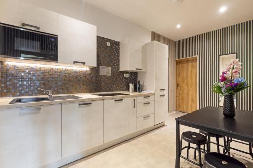 a kitchen with white cabinets and a table with a vase of flowers at Penzion Moon in Ostrava