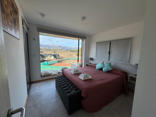 a bedroom with a bed and a large window at Departamentos Estancia Los Ñires in San Martín de los Andes