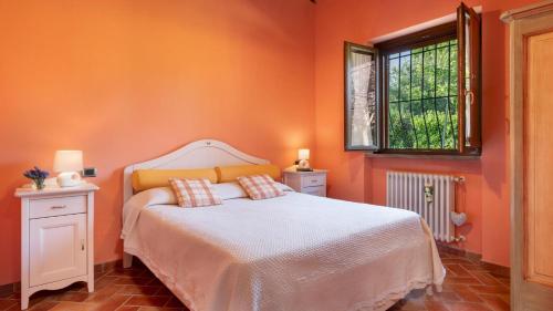 Dormitorio naranja con cama y ventana en Villa Peruccio Gioiello in Volterra, en Volterra