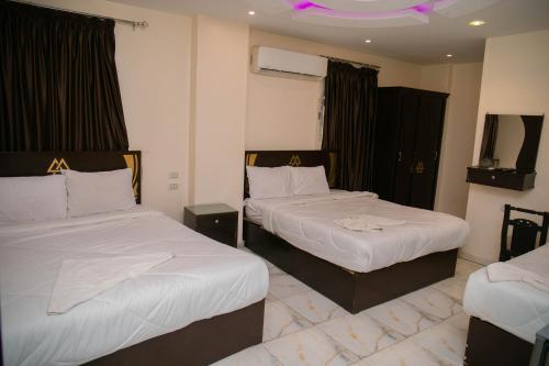 a hotel room with two beds with white sheets at Magic pYramidS HoTel in ‘Ezbet `Abd el-Ḥamîd