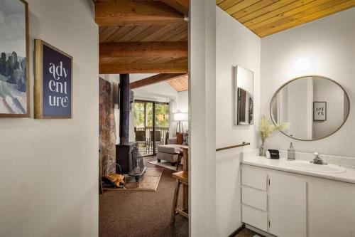 a bathroom with a sink and a mirror and a living room at Cedar Creek Cabin in Whitefish