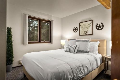 a bedroom with a large white bed with a window at Cedar Creek Cabin in Whitefish
