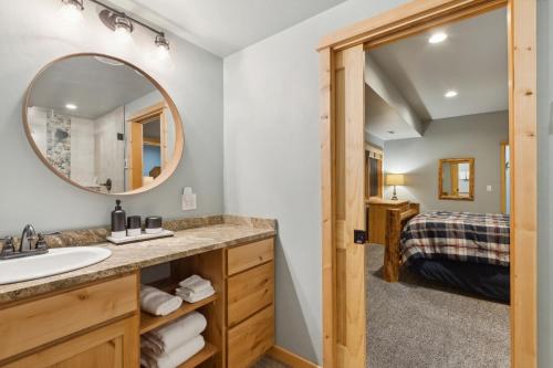a bathroom with a sink and a mirror and a bedroom at Whispering Pines in Whitefish