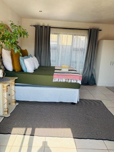 a bed sitting in a room with a window at KwaSihle Guesthouse in Dobsonville