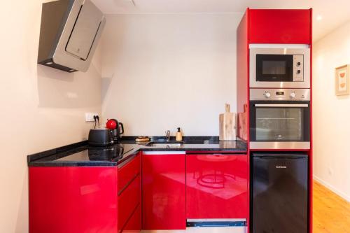 アジャンにあるStudio Épuré au Coeur de la ville d'Agenの赤いキッチン(黒いカウンタートップ、電化製品付)
