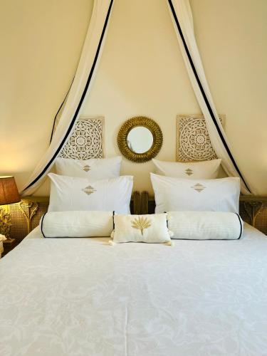 a large bed with white pillows and a mirror at Fabuleux! La Maison Au Bois Dormant in Barraux
