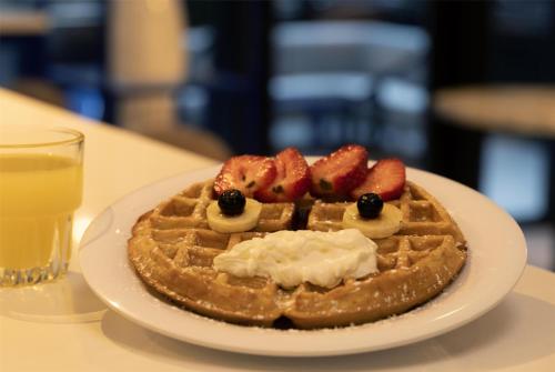 a plate with a waffle with strawberries and bananas at Best Western Premier Empire State Hotel in New York