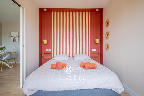 a bed with two orange pillows on top of it at Confort calme au Mans - Garage & ascenseur in Le Mans