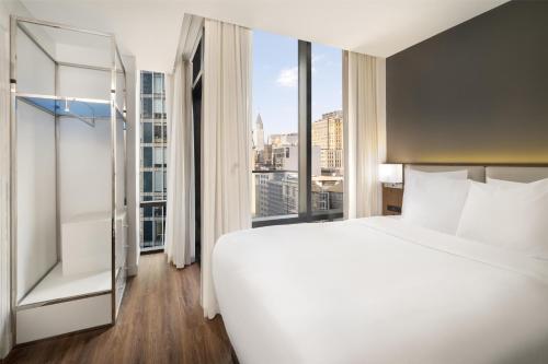 a bedroom with a large white bed and a large window at Best Western Premier Empire State Hotel in New York