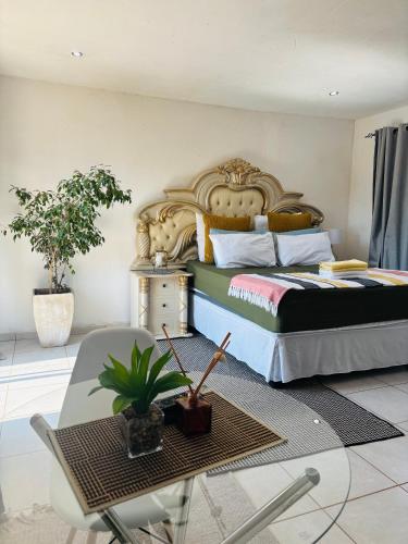 a bedroom with a king sized bed and a table and chair at KwaSihle Guesthouse in Dobsonville
