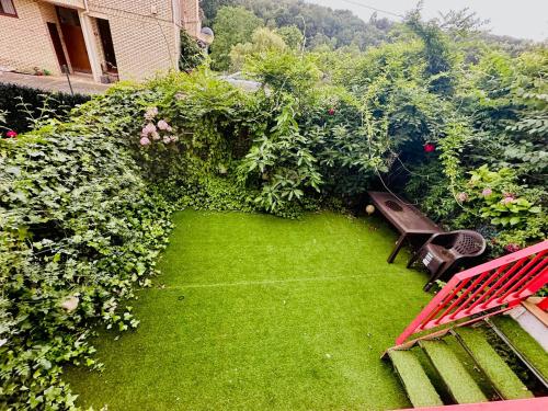 a garden with a red bench and green plants at Elegante Adosado en Ampuero in Rasines