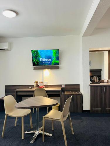 a room with a table and chairs and a tv on the wall at Hotel Le Paris in Noumea