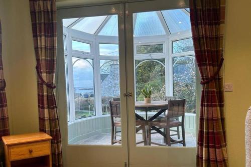a conservatory with a table and a glass door at 2 Guests - Garden & Patio - Sea Views in Strathcarron