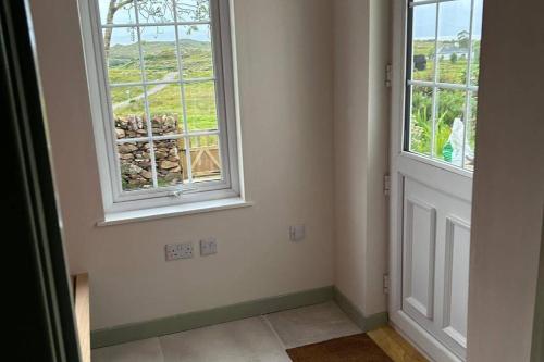 an empty room with two windows and a door at 2 Guests - Garden & Patio - Sea Views in Strathcarron