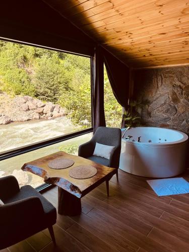 a room with a tub and a table and a chair at Ayder Luxury Villas & Bungalows in Çamlıhemşin