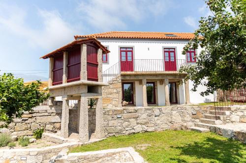 a house with red doors on a stone wall at Just Like Home - Casa Cesário in Vila Praia de Âncora